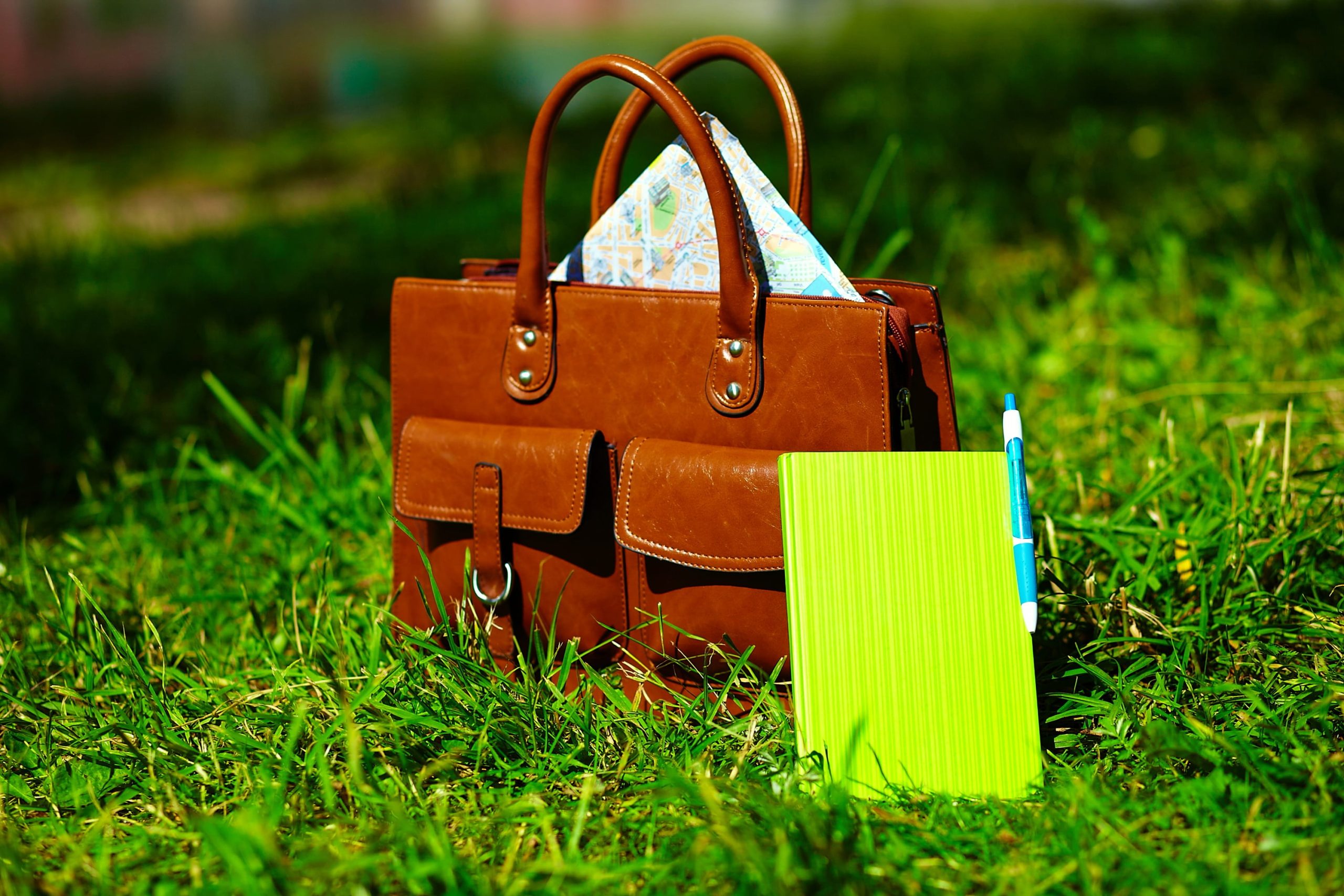 retro-brown-man-leather-bag-notebook-bright-colorful-summer-grass-park
